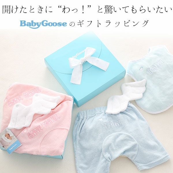 天使の羽デザインの名入れスタイとパンツのセット。ラッピングされたギフトボックスとともに展示
