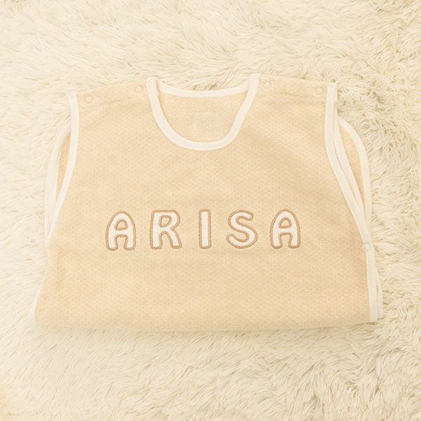 ベージュのスリーパーに白い糸でお名前刺繍が入った名入れ例
