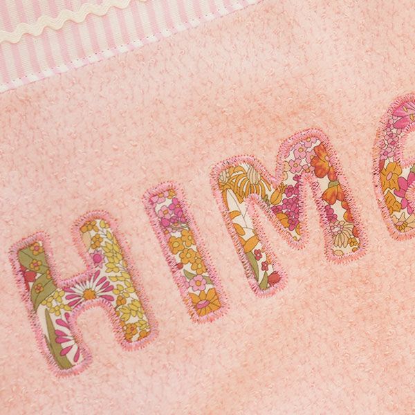 ピンクのタオルケットにカラフルな花柄で名入れ刺繍された例