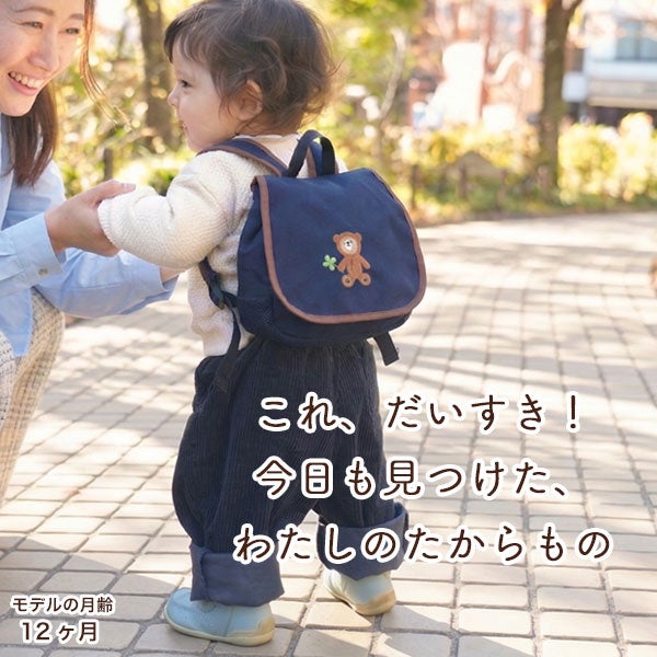 リュックを背負った赤ちゃんが母親と遊歩道を歩く様子