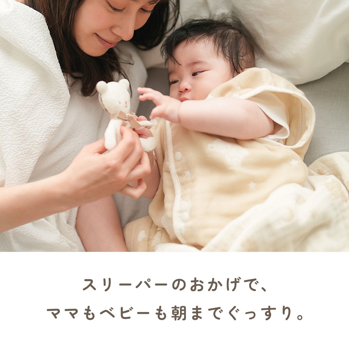 母親が赤ちゃんにベージュ色のガーゼスリーパーを着せている様子